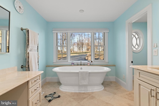 full bathroom with tile patterned floors, a freestanding bath, vanity, and baseboards