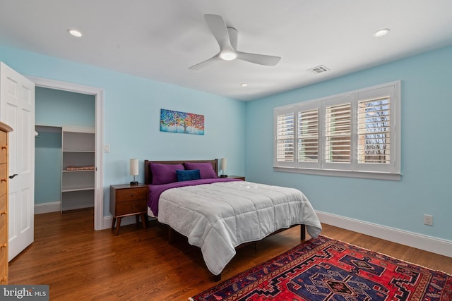 bedroom with visible vents, a walk in closet, wood finished floors, recessed lighting, and baseboards