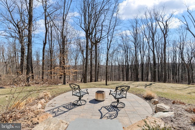 view of patio with a forest view and a fire pit