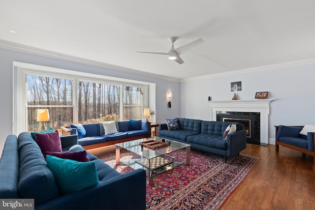 living room featuring a high end fireplace, crown molding, wood-type flooring, and ceiling fan