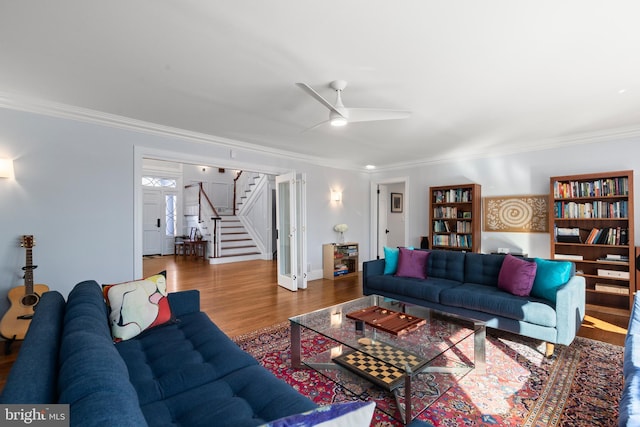 living room with wood finished floors, stairs, ceiling fan, and ornamental molding