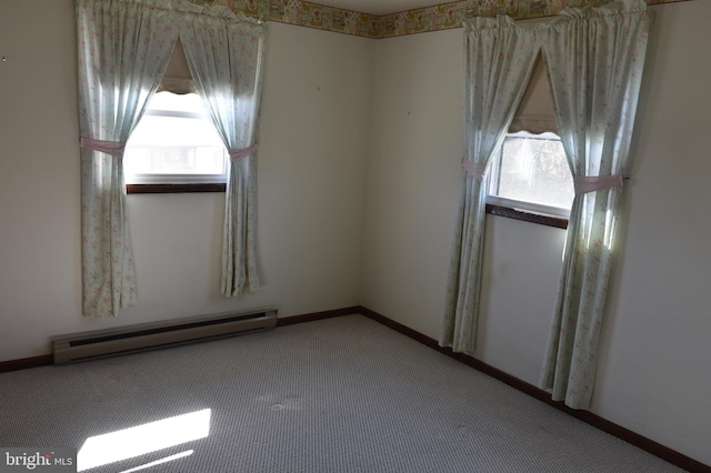 carpeted empty room featuring a baseboard heating unit and baseboards