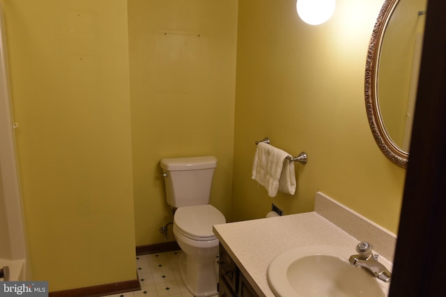 half bath with toilet, vanity, and baseboards