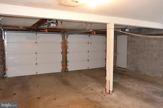 garage featuring concrete block wall and a garage door opener