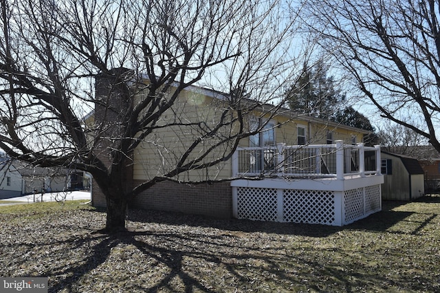 rear view of property with a wooden deck, a storage unit, and an outdoor structure