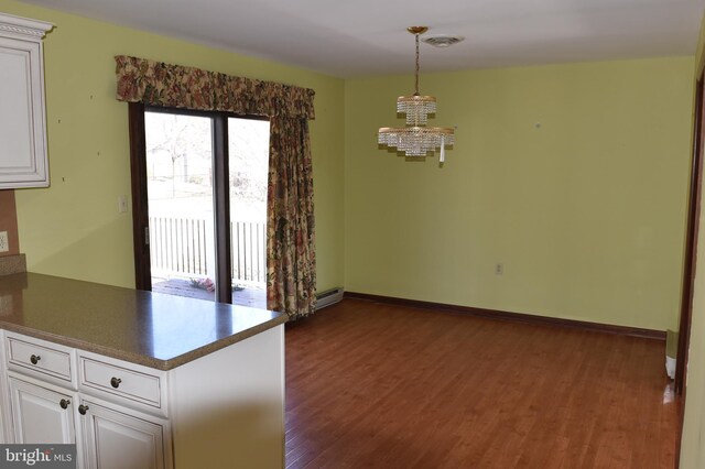 unfurnished dining area with dark wood finished floors, a notable chandelier, visible vents, and baseboards