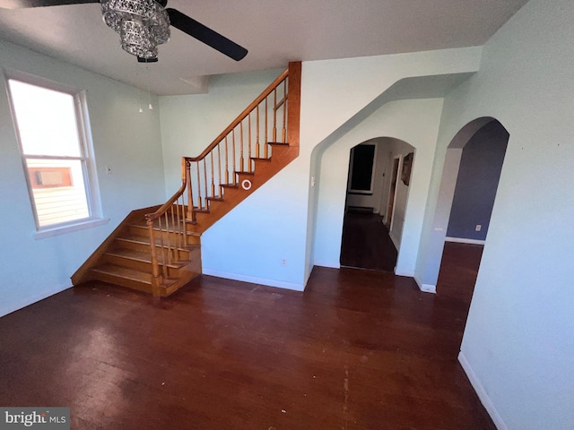 interior space with ceiling fan, baseboards, stairway, wood finished floors, and arched walkways