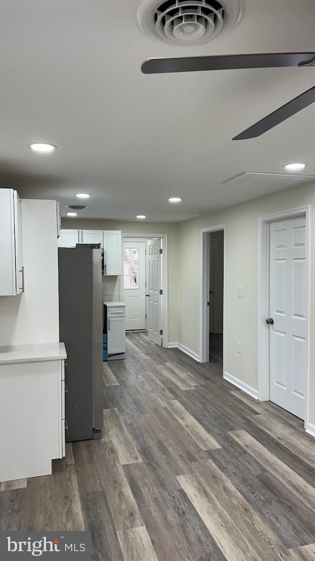 kitchen featuring dark wood-style floors, white cabinetry, freestanding refrigerator, light countertops, and baseboards