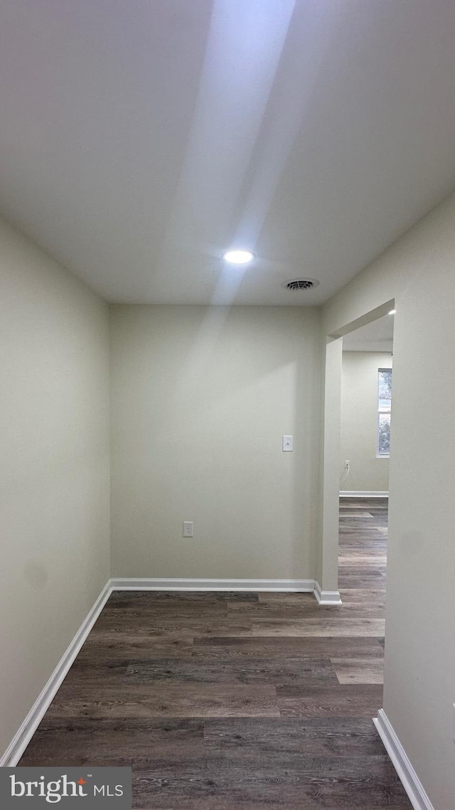 empty room featuring dark wood finished floors, visible vents, and baseboards