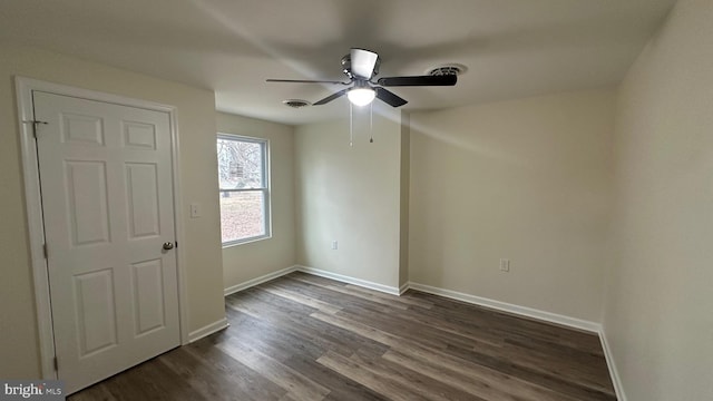 spare room featuring dark wood finished floors, visible vents, ceiling fan, and baseboards