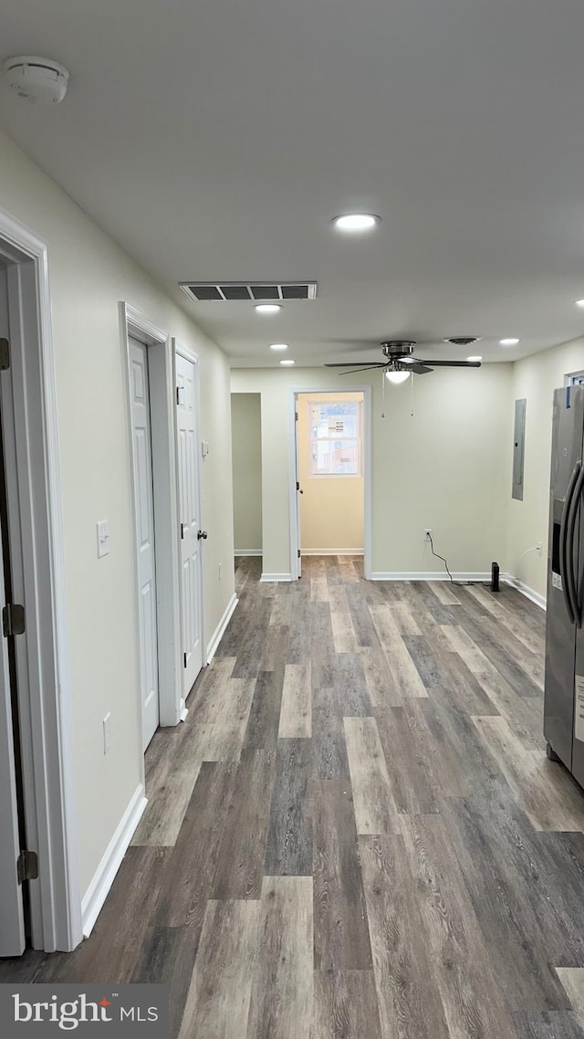 interior space featuring visible vents, a ceiling fan, electric panel, wood finished floors, and baseboards