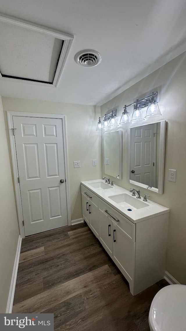 bathroom featuring double vanity, visible vents, wood finished floors, and a sink