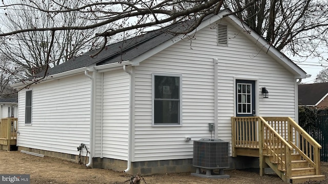 back of property with central AC and roof with shingles