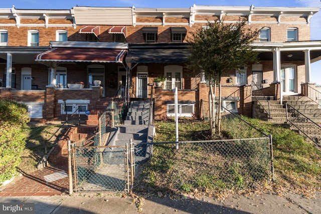 view of property featuring stairway, fence, brick siding, and a gate