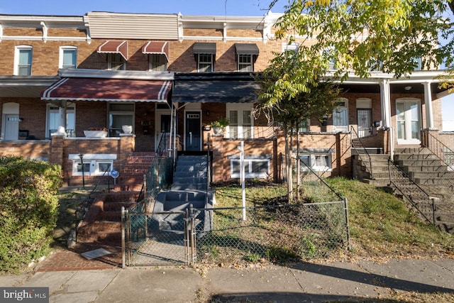 view of property featuring fence, brick siding, stairs, and a gate