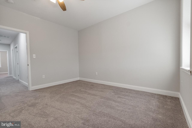 carpeted empty room featuring visible vents, a ceiling fan, and baseboards