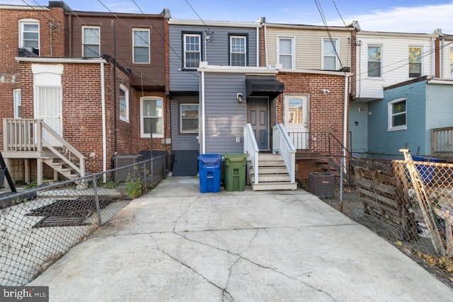 view of front of home with central AC unit, fence, and brick siding