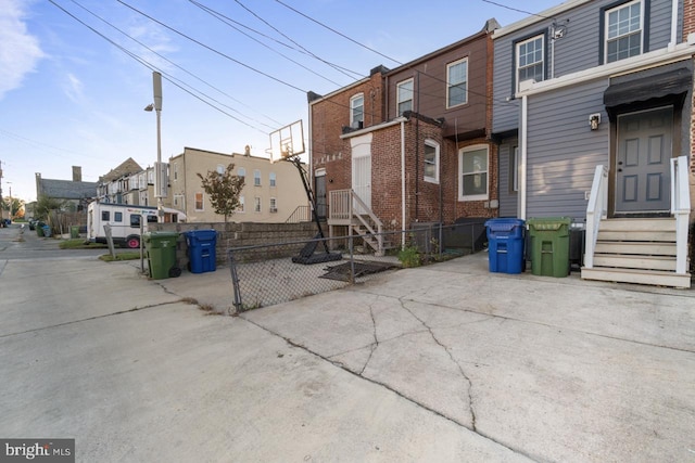 view of property exterior with brick siding, entry steps, and fence