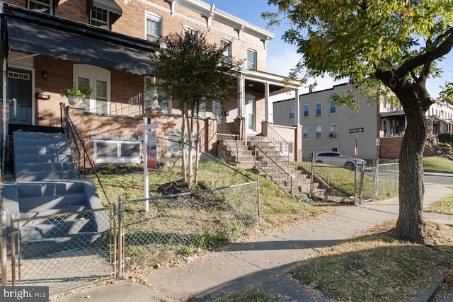 view of front of house with brick siding, covered porch, a fenced front yard, and a gate