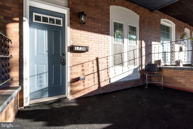 property entrance featuring brick siding and a porch