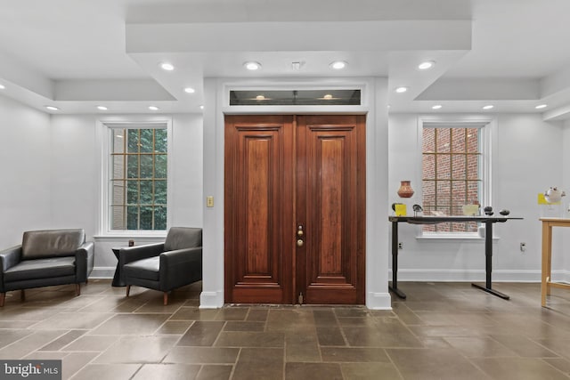 foyer featuring a tray ceiling, recessed lighting, and baseboards