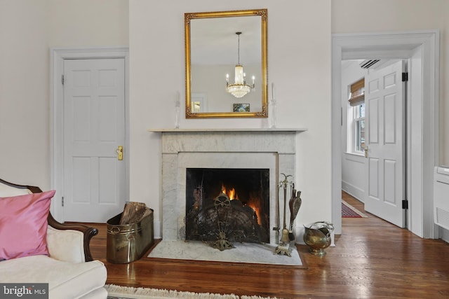 living room featuring an inviting chandelier, wood finished floors, and a fireplace