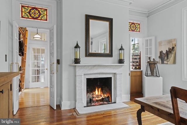 sitting room featuring a fireplace with flush hearth, wood finished floors, and crown molding