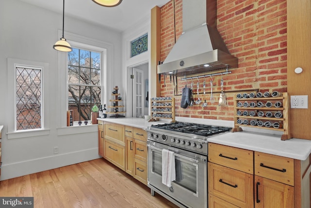 kitchen with range hood, baseboards, high end stove, light countertops, and light wood-style floors