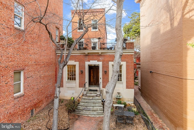 view of front facade featuring brick siding and a balcony