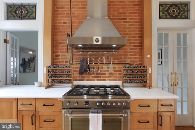 kitchen featuring french doors, ventilation hood, light countertops, and high end stainless steel range oven