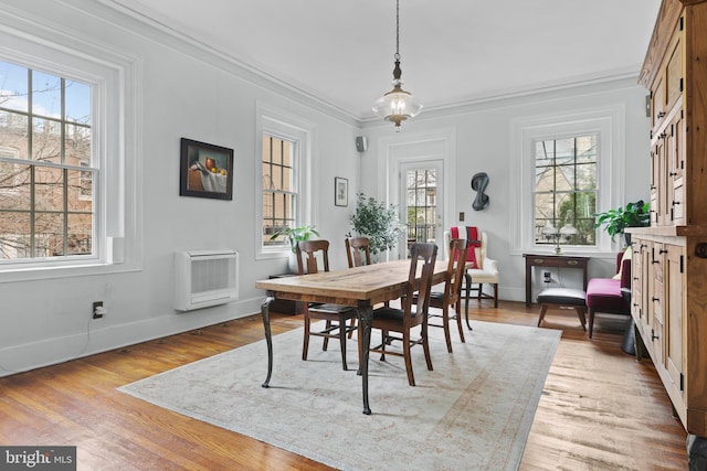 dining room with heating unit, baseboards, light wood-type flooring, and ornamental molding