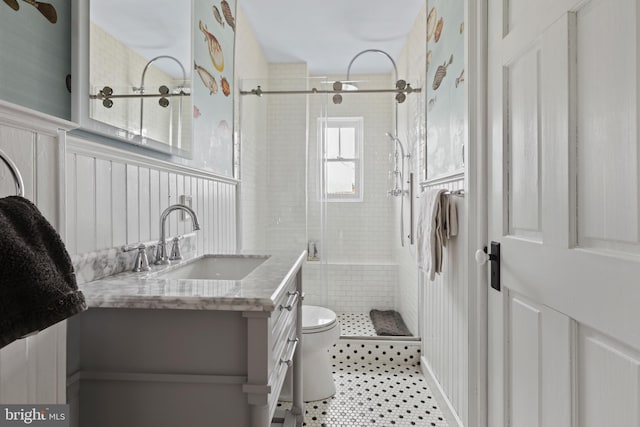 bathroom featuring vanity, a shower stall, wainscoting, tile patterned floors, and toilet