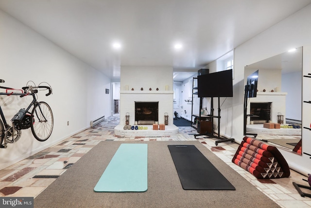 exercise room with a baseboard heating unit, baseboards, and a brick fireplace