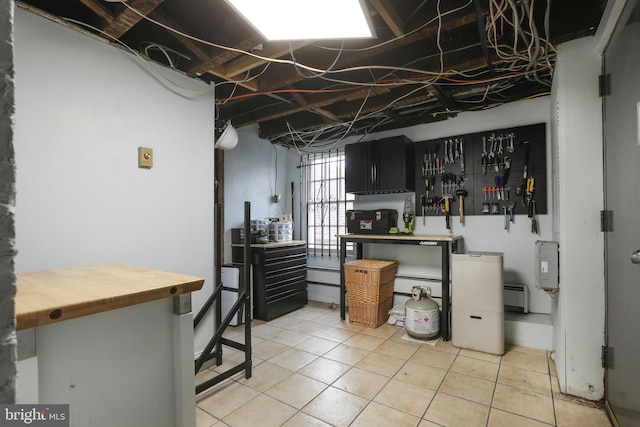 basement with light tile patterned floors and a baseboard radiator