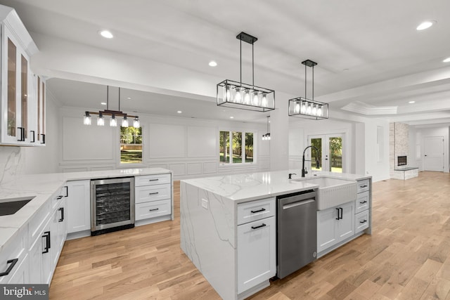 kitchen with a sink, stainless steel dishwasher, wine cooler, light wood-style floors, and a decorative wall