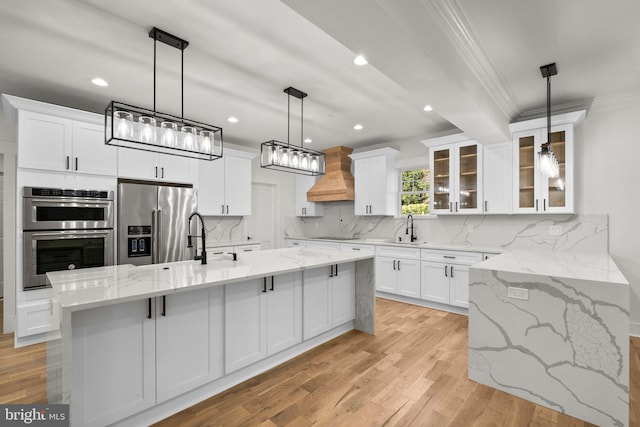 kitchen featuring a sink, stainless steel appliances, custom exhaust hood, and white cabinets