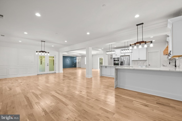 kitchen with light wood-type flooring, ornamental molding, stainless steel refrigerator with ice dispenser, open floor plan, and white cabinetry