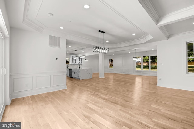 unfurnished living room featuring a sink, a decorative wall, visible vents, and ornamental molding