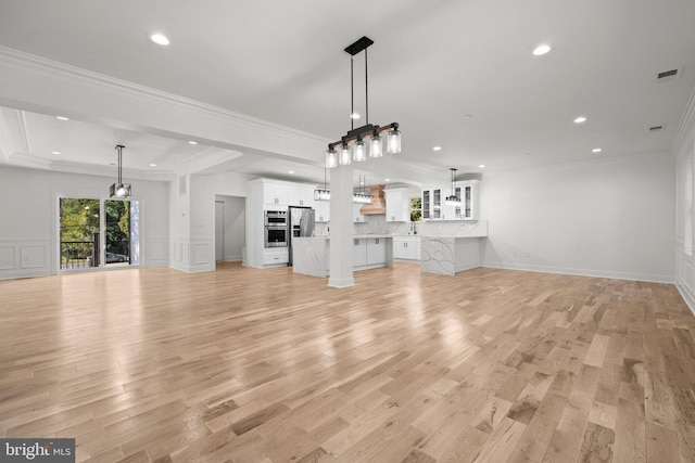 unfurnished living room featuring visible vents, ornamental molding, recessed lighting, light wood-style flooring, and a decorative wall