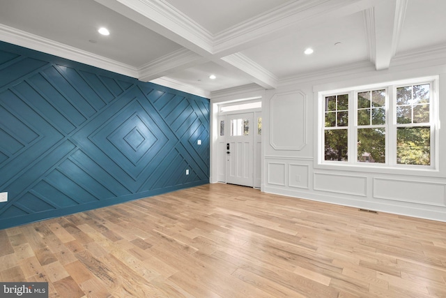 interior space featuring crown molding, beamed ceiling, a decorative wall, and light wood-style floors