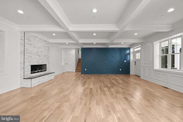 unfurnished living room featuring beamed ceiling, coffered ceiling, stairway, a fireplace, and light wood finished floors