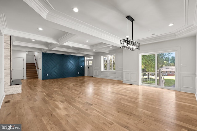 unfurnished living room featuring stairway, beamed ceiling, visible vents, a decorative wall, and light wood-type flooring