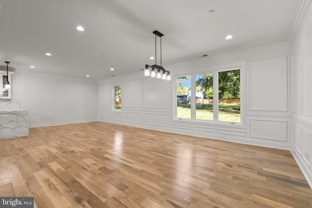 unfurnished living room featuring visible vents, light wood finished floors, recessed lighting, ornamental molding, and a decorative wall