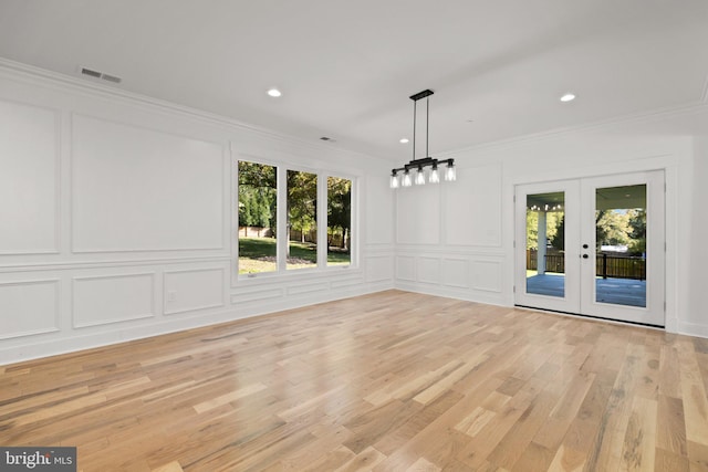 unfurnished dining area featuring a wealth of natural light, a decorative wall, french doors, and crown molding