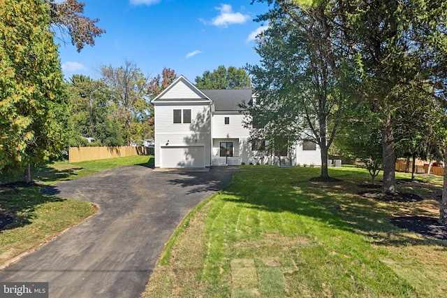 view of front facade with aphalt driveway, a garage, fence, and a front lawn