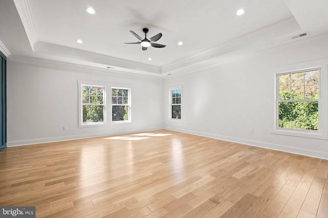 spare room featuring visible vents, light wood-style flooring, a raised ceiling, and ornamental molding