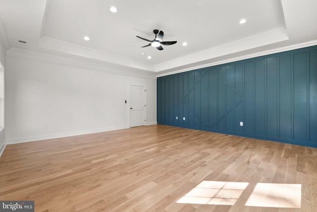 spare room featuring ceiling fan, a tray ceiling, ornamental molding, and light wood finished floors