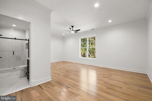 interior space with light wood-style flooring, baseboards, crown molding, and a barn door