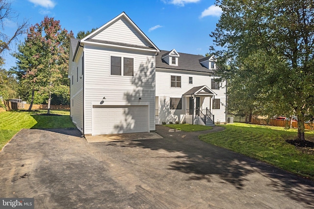 view of front of house featuring aphalt driveway, a garage, a front lawn, and fence