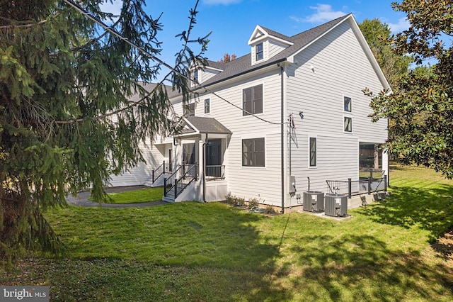 rear view of property with a lawn and central AC